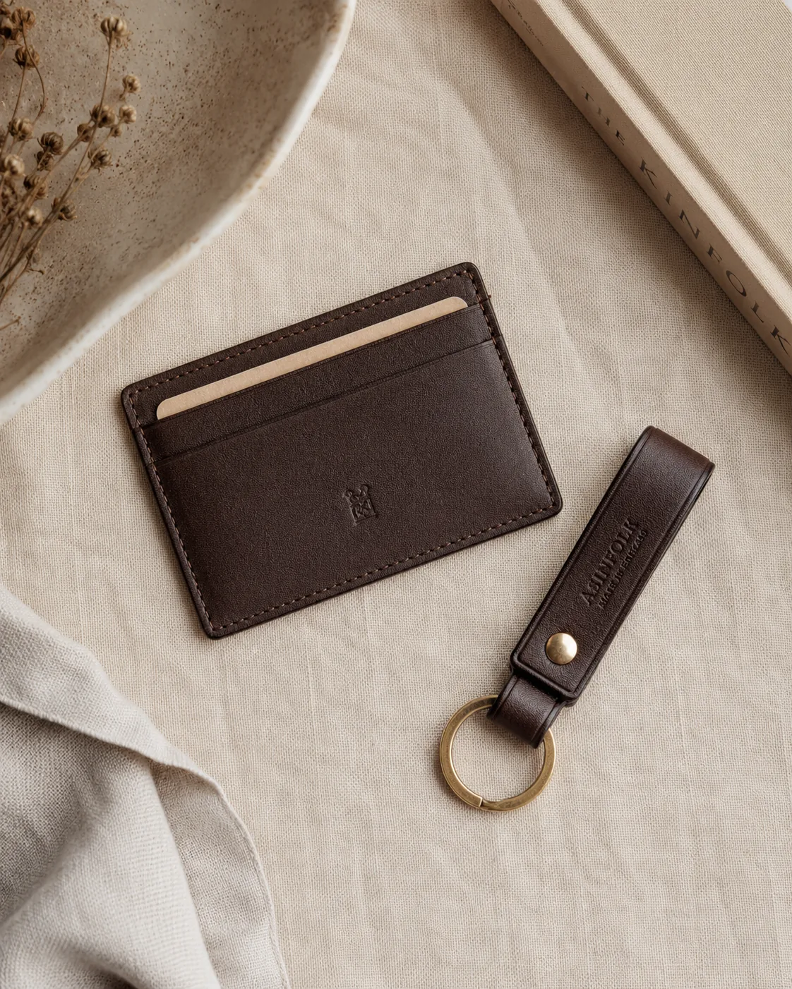 Leather card case and key fob on warm linen