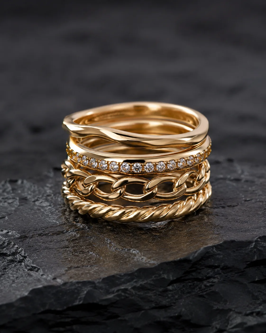 Stack of gold rings on dark stone surface