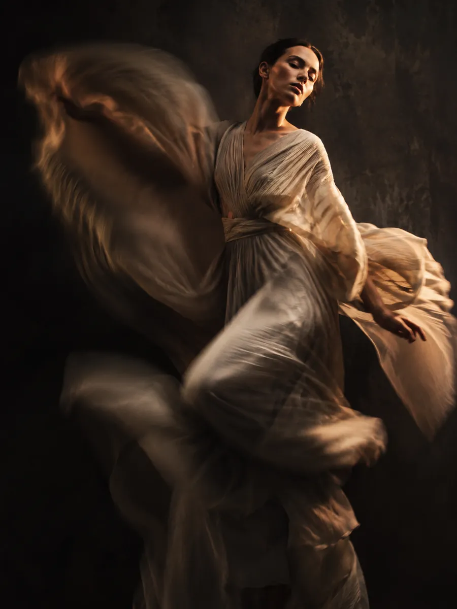 Editorial apparel shot — a draped garment in a dark studio