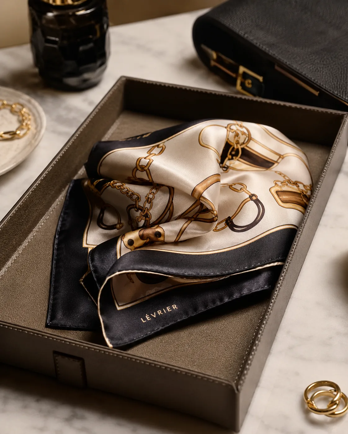 Patterned silk scarf in a leather tray, marble surface
